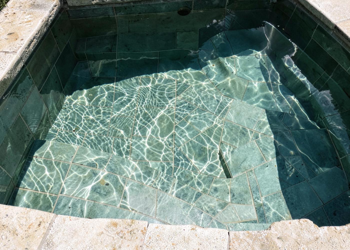 Agua clara sobre el acabado cerámico del fondo y las escaleras de una piscina