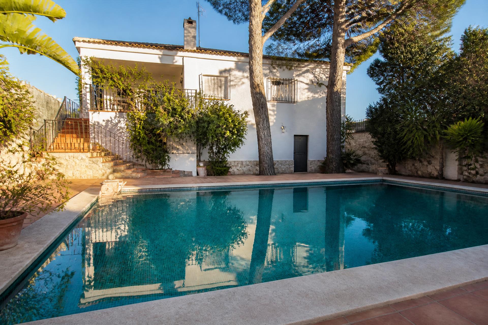 Piscina privada de obra con acabado cerámico en el jardín de un chalet mediterráneo
